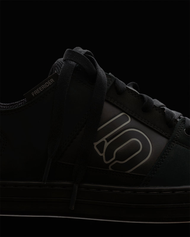 A closeup image of the centre section of a black cycling shoe. It is very selectively and subtly lit. Photographed by professional product photographer Mike Taylor in his studio in Peterborough Ontario Canada.
