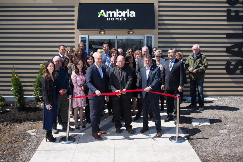 A group of people stand in front of a real estate presentation centre, about to cut the opening ribbon. Shot by business photographer Mike Taylor in Peterborough Ontario.