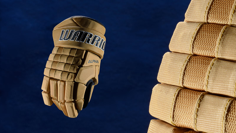 An image of a sand-coloured hockey glove against a dramatic blue background. It is dramatically lit by product photographer Mike Taylor in his Peterborough Ontario studio.