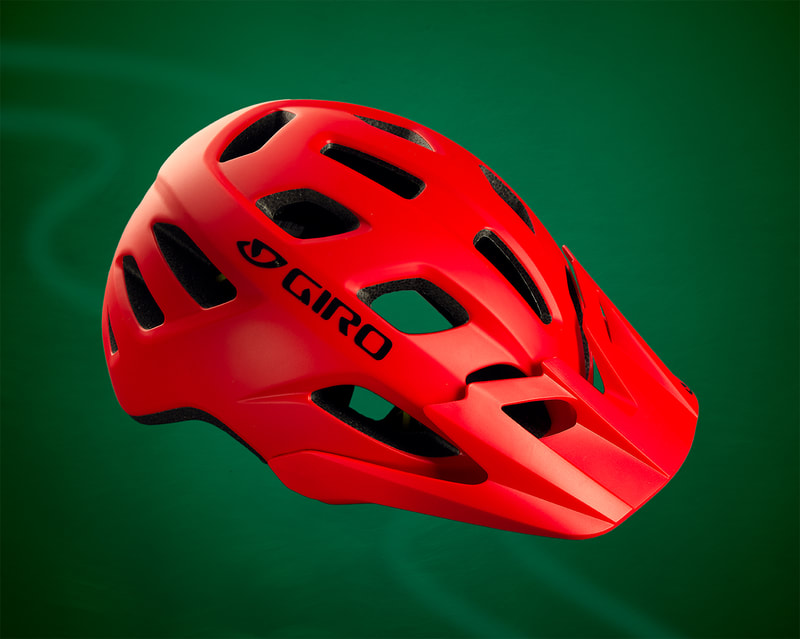 A red Giro bicycle helmet floats in front of a green background. Shot by product photographer Mike Taylor in Peterborough Ontario.